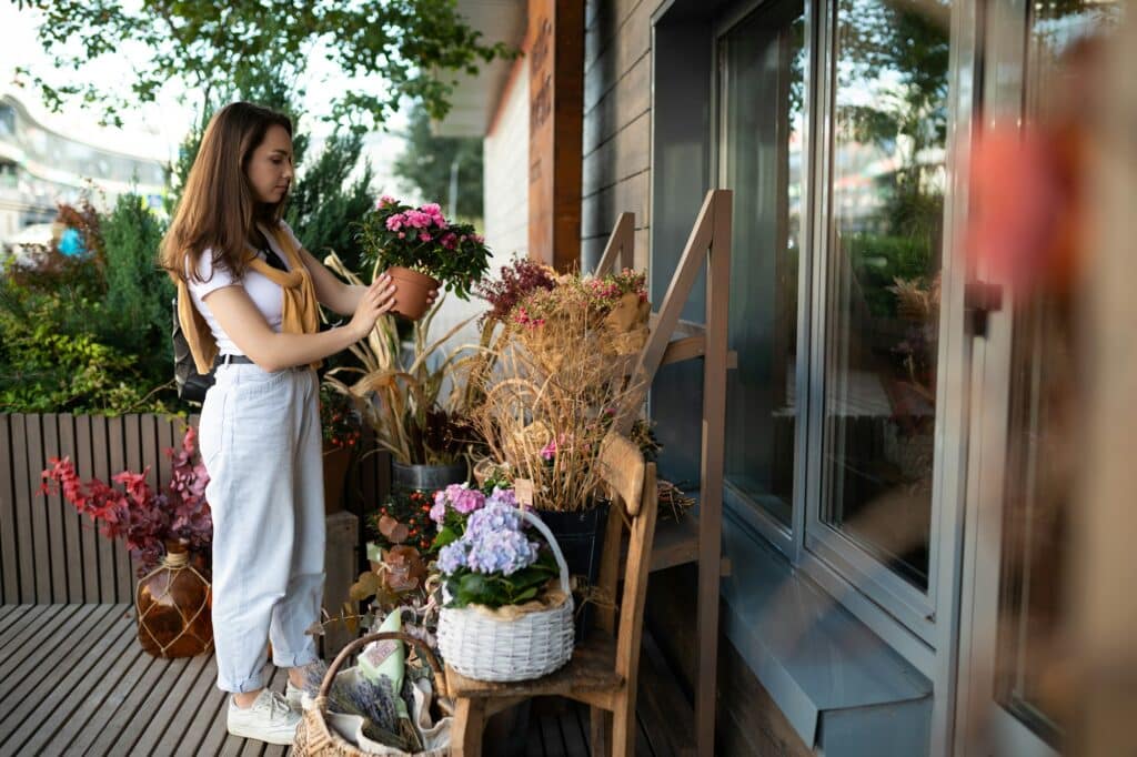 happy caucasian young woman chooses potted flowers to buy at outdoor garden stall
